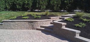 “Backyard landscape featuring mulch ground cover and neatly built retaining walls for structure and support.”