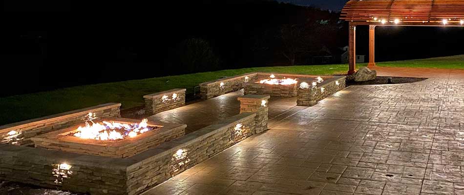 Outdoor living area with seating walls, a fire pit, and outdoor lighting in Mt. Juliet, TN.